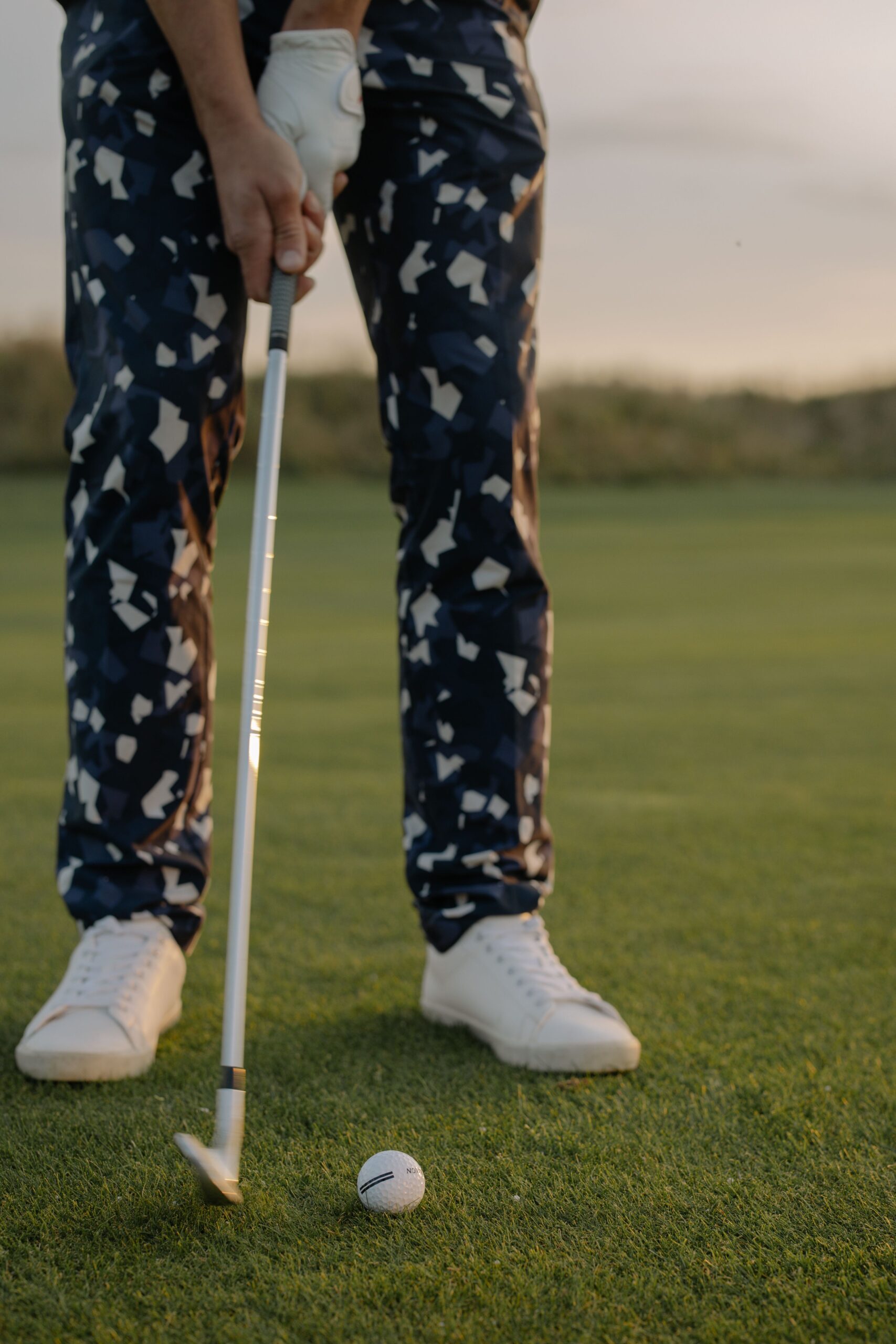 A golfer poised to hit a ball on a sunny golf course.